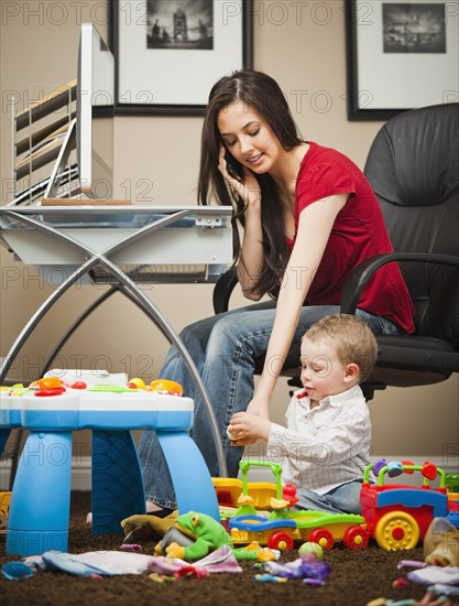 Caucasian woman tending child and working in home office