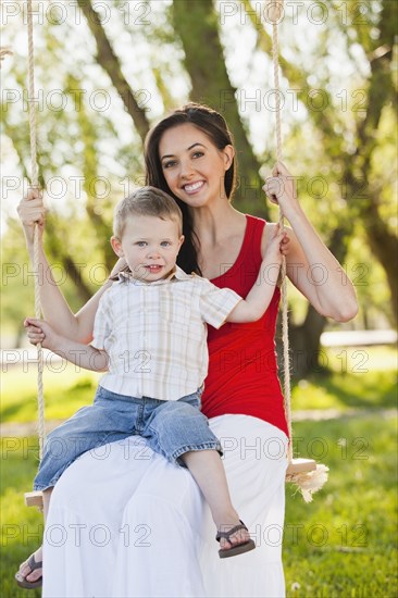 Caucasian mother and son swinging together
