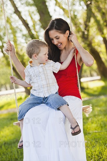 Caucasian mother and son swinging together