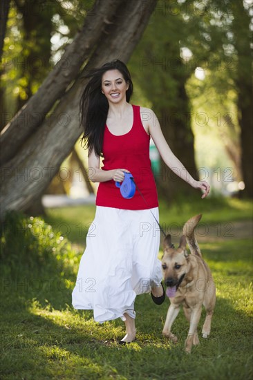 Caucasian woman walking dog in park