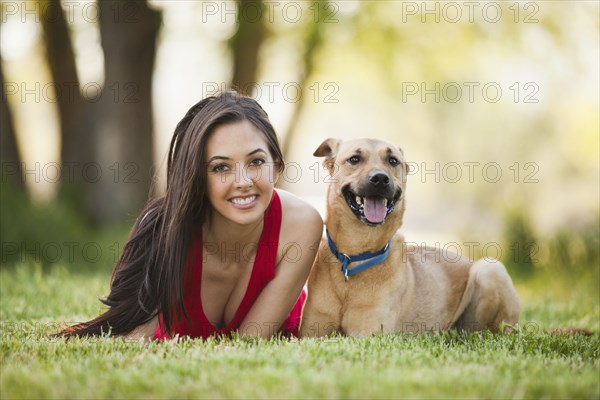 Caucasian woman laying in grass with dog