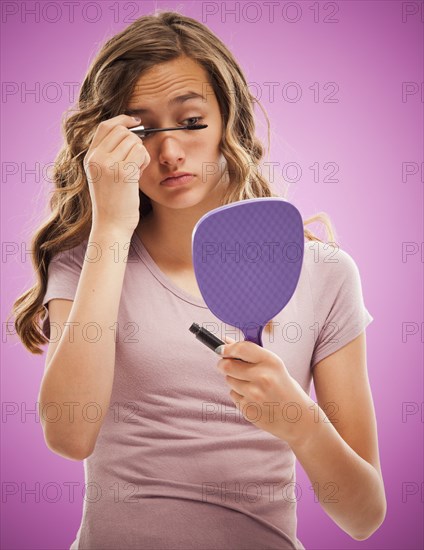 Caucasian teenager putting on mascara