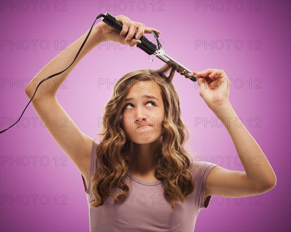 Caucasian teenager curling her hair