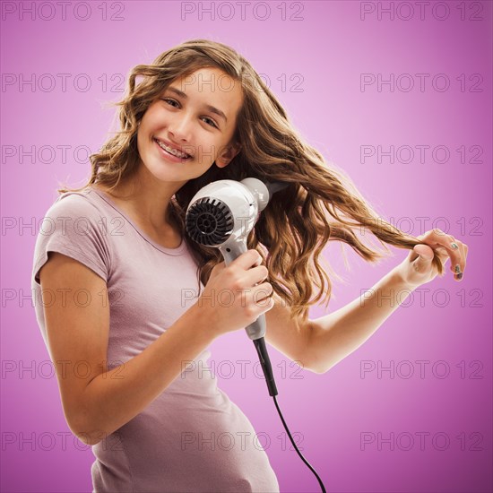 Caucasian teenager blow drying her hair