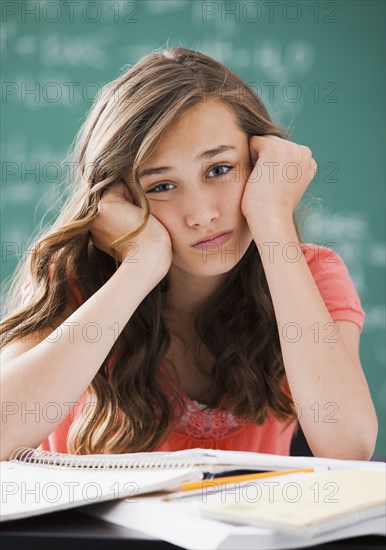 Bored Caucasian teenager studying on classroom