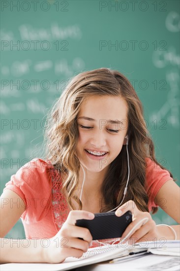 Caucasian teenager listening to mp3 player in classroom