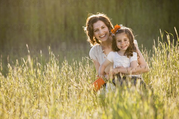 Caucasian mother and daughter sitting in grass