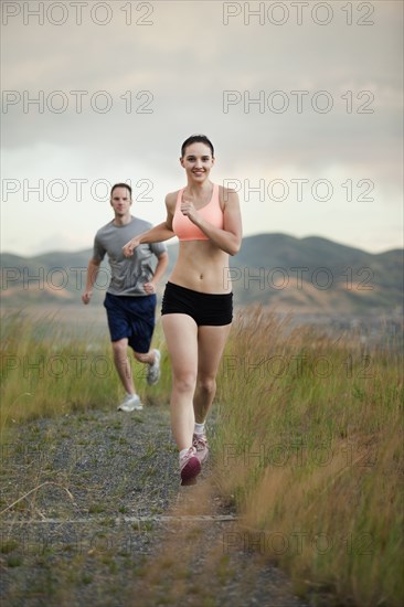 Caucasian couple running together on remote path