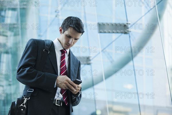 Caucasian businessman text messaging on cell phone outdoors