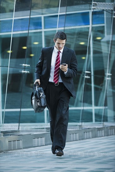 Caucasian businessman text messaging on cell phone outdoors