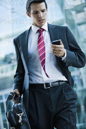 Caucasian businessman looking at cell phone outdoors