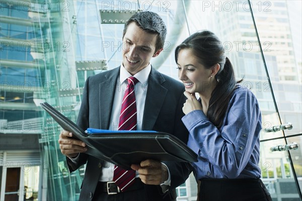 Caucasian business people looking at notebook together