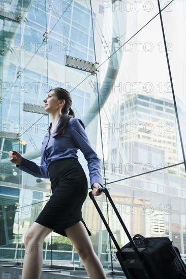 Caucasian businesswoman pulling suitcase outdoors