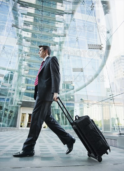 Caucasian businessman pulling suitcase outdoors