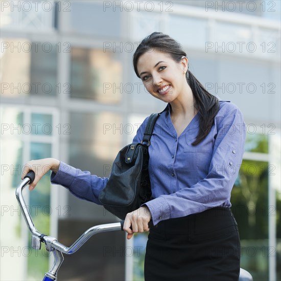 Caucasian businesswoman riding bicycle