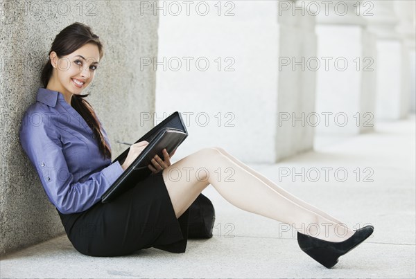 Caucasian businesswoman writing in notebook outdoors