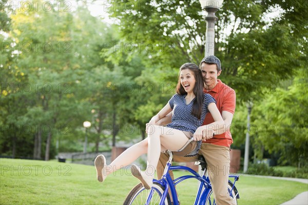 Caucasian couple riding bicycle together