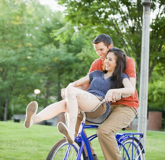 Caucasian couple riding bicycle together