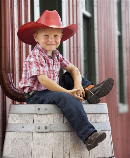 Caucasian cowboy sitting on barrel