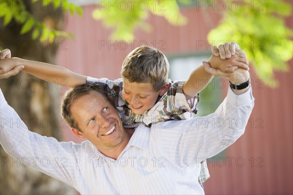 Caucasian father carrying son on his shoulders