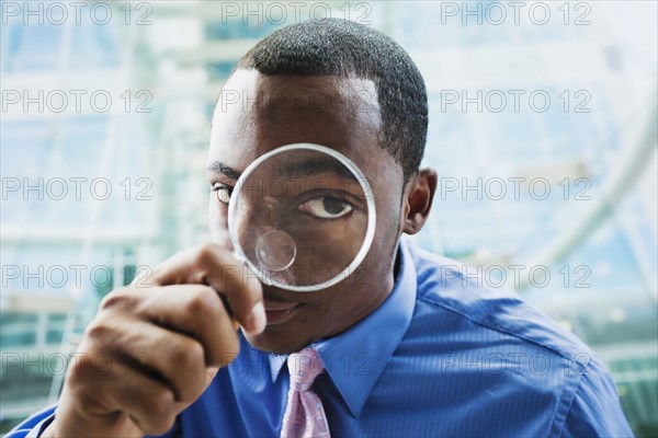 Black businessman using magnifying glass