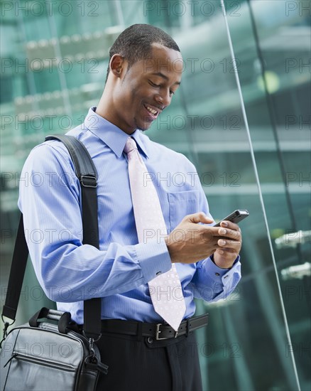 Black businessman text messaging on cell phone