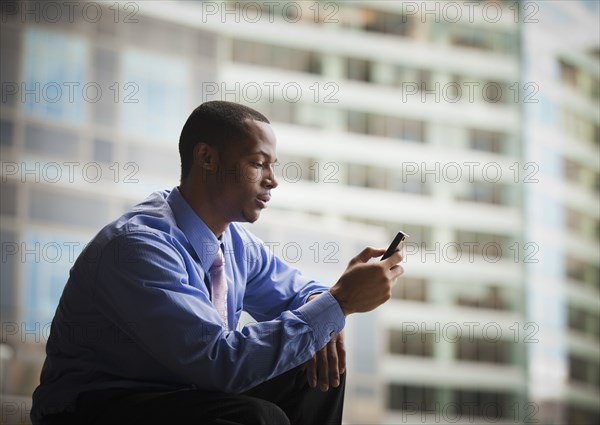 Black businessman text messaging on cell phone