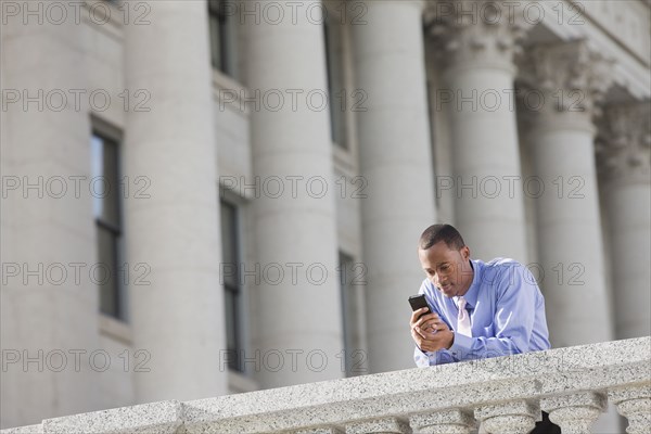 Black businessman text messaging on cell phone