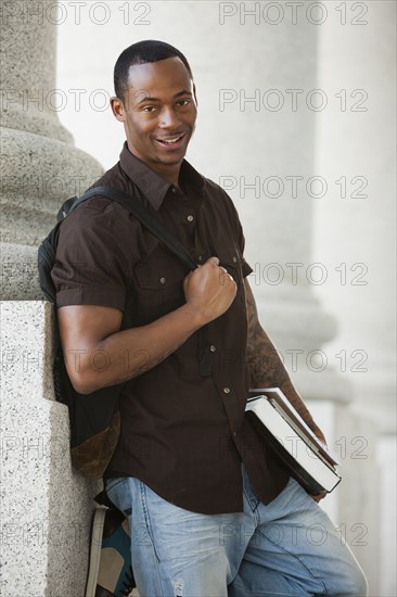 Black college student holding books outdoors