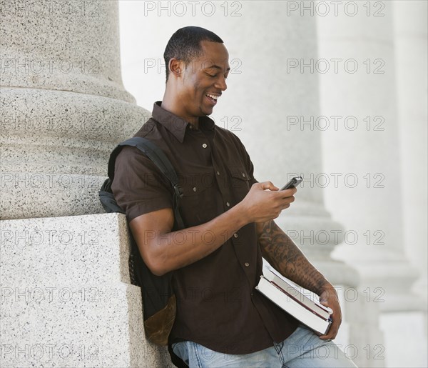 Black college student text messaging on cell phone