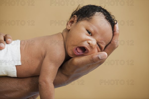 Father cradling newborn baby in hand