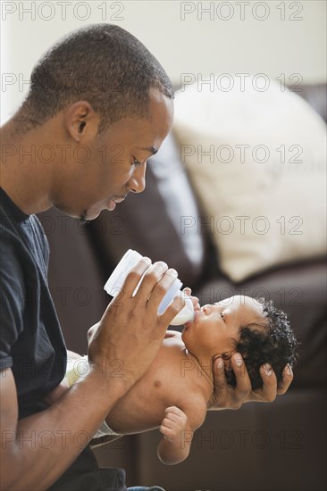Father feeding bottle to newborn baby