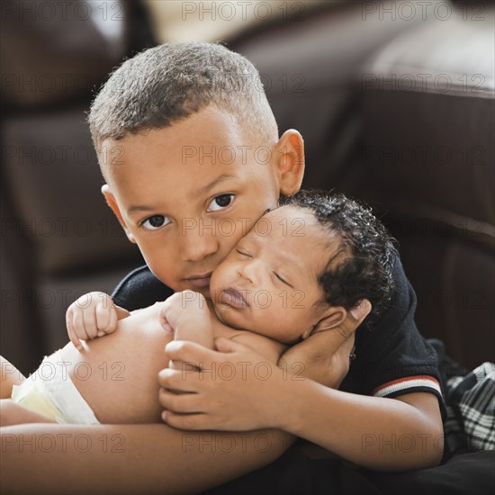 Mixed race boy hugging newborn baby