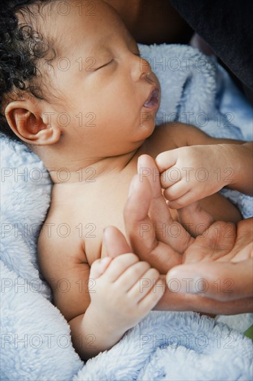 Father holding hands with newborn baby