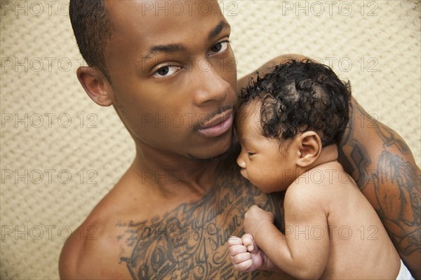 Tattooed father holding newborn baby