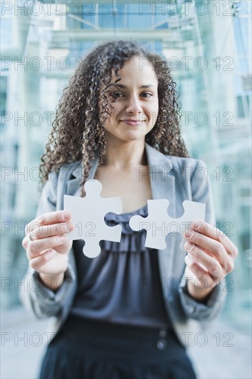 Caucasian businesswoman holding jigsaw puzzle pieces