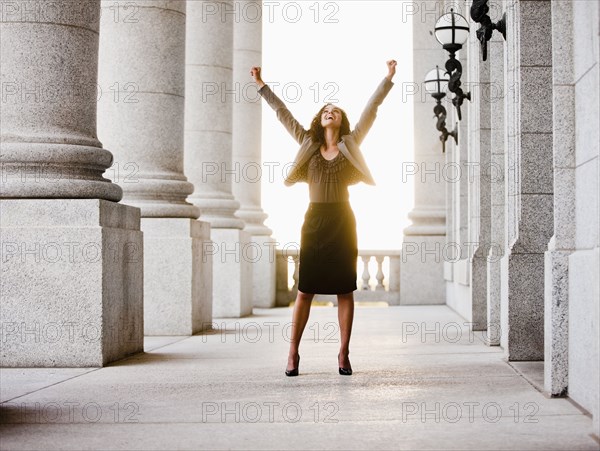 Caucasian businesswoman cheering outdoors with arms raised