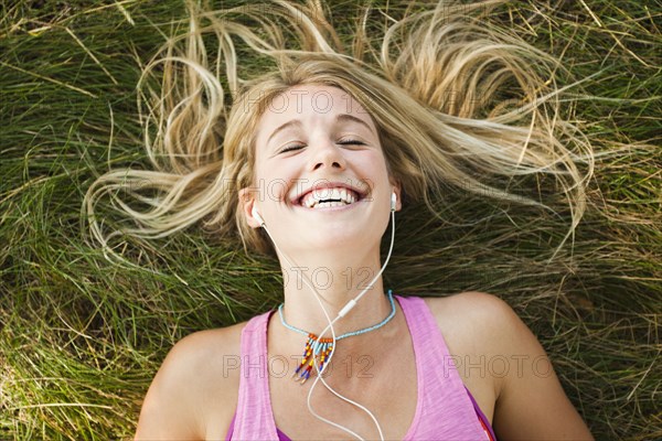 Caucasian woman laying in grass listening to music