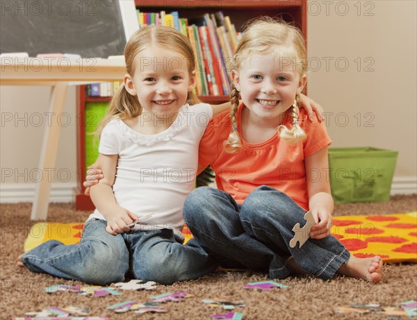 Caucasian sisters putting together puzzle