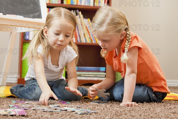 Caucasian sisters putting together puzzle