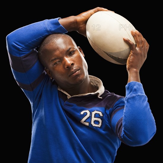 African American athlete holding rugby ball