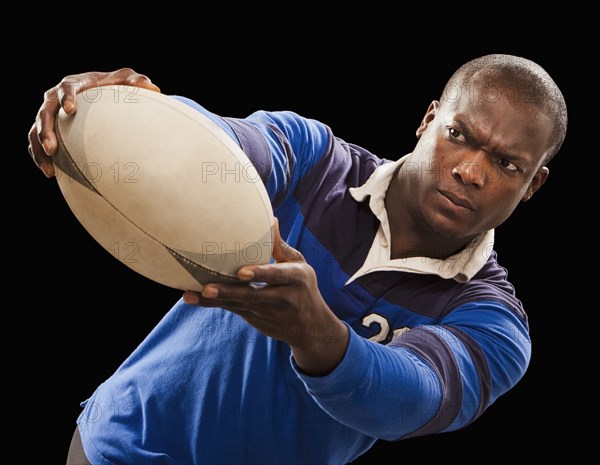 African American athlete holding rugby ball