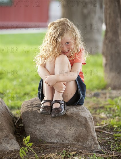 Smiling Caucasian girl sitting on rock