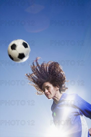 Caucasian woman heading soccer ball