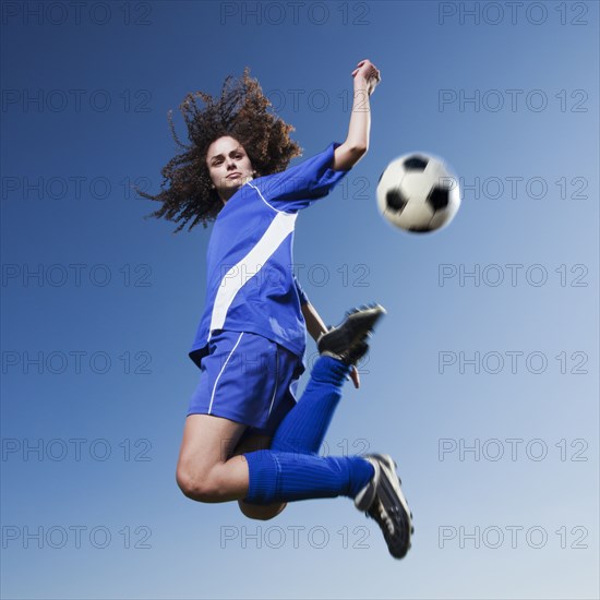 Caucasian woman kicking soccer ball