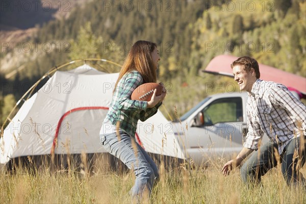 Caucasian couple playing football at campsite