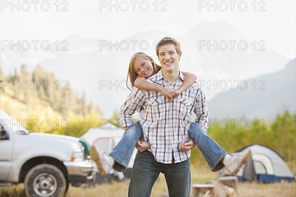 Caucasian father giving daughter piggy back ride