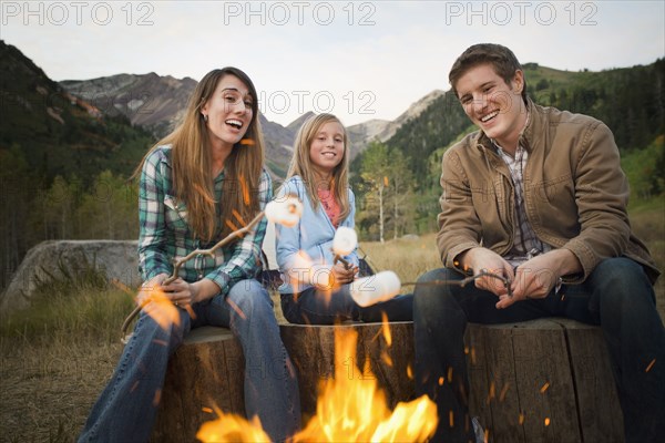 Caucasian family roasting marshmallows on campfire