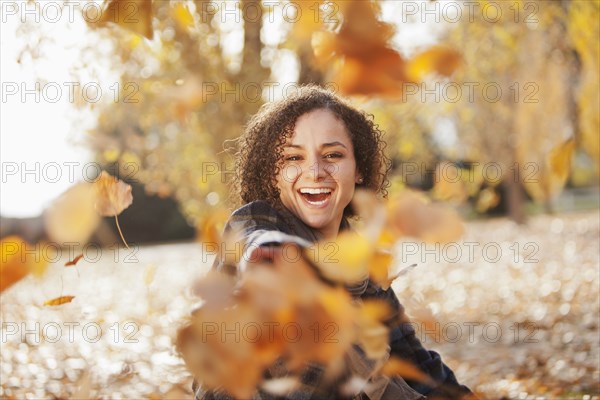 Caucasian woman playing in autumn leaves