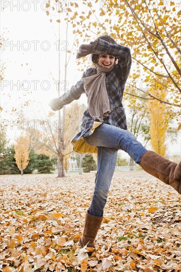 Caucasian woman playing in autumn leaves